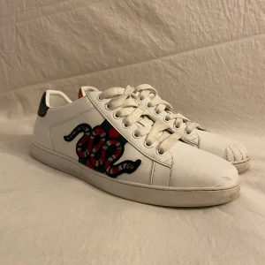 Gucci Ace vita sneakers med orm - Gucci ace snake som är köpta denna sommar. Är i storlek 41 men passar definitivt dig med 42. Snygga å fräscha men finns en defekt på framsidan av vänstra skon. Priset är inte hugget i sten!