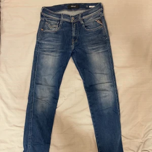 Replay Anbass jeans - Snygga blå Replay Anbass jeans med klassisk femficksdesign. Jeansen har läderpatch bak och Replay-logga på myntfickan. Modellen är midwaist och tillverkad i mjukt denimtyg som sitter skönt hela dagen. Vid frågor eller liknande är det bara att höra av sig!