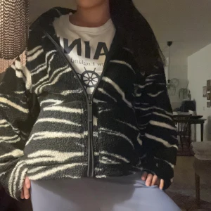  Zebra Teddyjacka - Säljer en svart teddyjacka från HM i storlek S med vit zebramönstrad design. Jackan har dragkedja framtill, långärmade ärmar och är gjord i mjukt fleece-material. Perfekt för dig som vill sticka ut med en cool och mysig look.