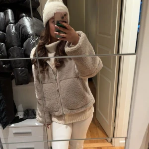 Beige teddyjacka med dragkedja - Säljer en beige teddyjacka med mjuk och fluffig känsla, perfekt för kalla dagar. Jackan har en rak, loose passform och stängs med dragkedja framtill. Den har långa ärmar och en enkel, stilren design som är lätt att matcha med olika outfits.