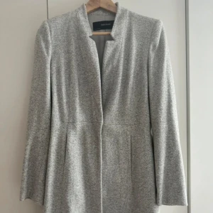 Grå kappa med fickor från Zara - Säljer en snygg grå kappa från Zara. Kappan har en knapp i mitten