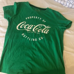 Grön Coca-Cola t-shirt med tryck - Snygg grön t-shirt i storlek 170 med stort vitt coca cola tryck på bröstet som jag köpte på gekås för 2 år sedan.
