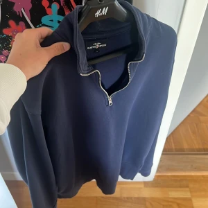Marinblå half zip tröja Hampton Republic - Snygg marinblå långärmad tröja från Hampton Republic med half zip-dragkedja i halsen. Tröjan har en enkel och clean look, perfekt för chill dagar. Materialet är mjukt och känns skönt mot huden. Passformen är normal och funkar till de flesta stilar.