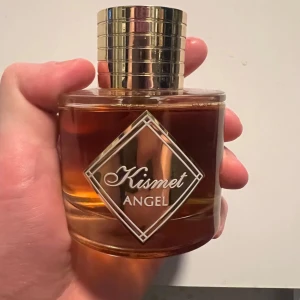 Kismet Angel Parfym - Kismet Angel från Maison Alhambra – en lyxig och förförisk doft som omfamnar dig med varm vanilj, kryddig kanel och söt karamell. Den öppnar med rika toner av honungskaka och amber, innan den djupnar i en sensuell mix av cognac, tonkaböna och mörk choklad.  Perfekt för dig som älskar eleganta och djupa dofter med en lyxig känsla. Passar både kvinnor och män!