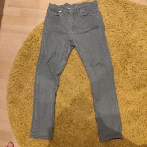 Gråa slim jeansbyxor - Säljer ett par gråa jeansbyxor med klassisk femficksdesign och smal passform. Byxorna har normal midja och raka ben, perfekta för en clean och stilren look. Materialet är mjukt och följsamt, vilket gör dem bekväma hela dagen.