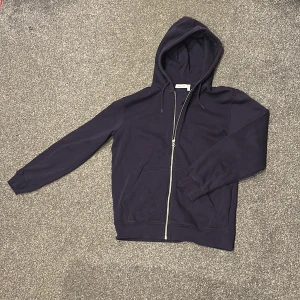 Lila hoodie från Weekday XS - Säljer en lila hoodie från Weekday i storlek XS. Tröjan är i otroligt bra skick nästan som helt ny.  Nypris ca 700 kr. Tröjan har dragkedja framtill, huva med snörning och två fickor. Tillverkad i mjuk bomull och riktigt skön att ha på sig.  