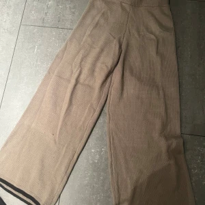 Beige stickade wide byxor - Snygga beige stickade byxor med breda ben och svart kant längst ner. Perfekta för en chill och trendig look. Mjukt stickat material som känns skönt mot huden och ger en avslappnad vibe. Inte säker på vart dessa är ifrån men tror Shein.