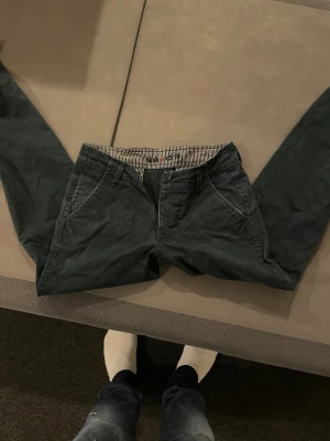 Mörkblå chinos från NN07, 28/34 - Snygga mörkblå chinos från NN07 i modellen Simon. Byxorna är tillverkade i 100% bomull och har klassiska snedställda fickor fram samt randigt innerfoder i midjan. Perfekta för när du vill vara lite extra stilig till exempel på Jul eller Nyår🎅🎅