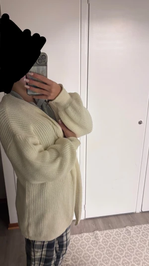 Beige stickad kofta med omlott - Mysig beige stickad kofta med omlott-design och långa ärmar. Koftan har en loose passform och är tillverkad i ett grovt stickat material som ger en chill och avslappnad vibe. Perfekt att slänga på sig när det är lite kyligt ute. 