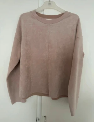 Puderrosa loose sweatshirt i mockaimitation - Säljer en puderrosa sweatshirt med loose passform och långärmade ärmar. Tröjan har en rak passform, och rund hals och är gjord i mjuk mockaimitation som ger en lyxig känsla. Perfekt för dig som gillar stilrena och enkla plagg