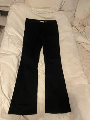 Lågmidjade Bootcut jeans - Snygga svarta lågmidjade jeans med bootcut passform och klassisk midja. Modellen heter Cindy och har en stilren look med lätt utsvängda ben. Materialet är mjukt och bekvämt, perfekt för dig som gillar en tidlös och cool stil. ALDRIG ANVÄNDA
