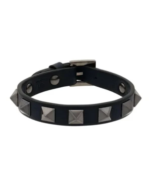 Svart armband med nitar från Valentino - Coolt svart armband från Valentino i skinn med silvriga pyramidformade nitar runt om. Armbandet har ett justerbart spänne i metall och ger en edgy vibe till din stil. Perfekt för dig som gillar att sticka ut med accessoarer. Skriv för egna bilder, köpt på vinted! Box medföljer!