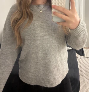 Grå stickad tröja - Mysig grå stickad tröja. Tröjan har en enkel och clean look, perfekt för dig som gillar basic vibes. Långärmad modell med normal passform, passar till allt och är superenkel att styla. Har dock ett litet hål vid armen (går att fixa)