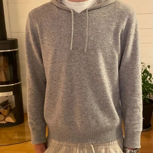 Grå hoodie i kashmir från Sayless - Mjuk och lyxig grå hoodie från Sayless i kashmir. Tröjan har huva med snörning, ribbade muddar och långärmad passform. Perfekt för dig som gillar stilren och chill look. Snygg att matcha med både jeans och mjukisbyxor. Säljer hoodien då den har blivit för liten helt enkelt. Inga synbara defekter utan i mycket god skick. Hör av er om ni har några funderingar!