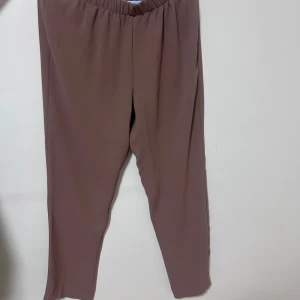 Bruna loose byxor med resårmidja - Snygga bruna byxor. Tillverkade i ett mjukt och lätt material som ger en skön känsla. Perfekta för en chill och stilren look.