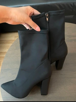 Svarta stövletter med klack - Snygga svarta stövletter med spetsig tå och hög klack. Skorna har dragkedja på sidan. Fint skick 