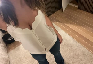 Vit linnetopp med scallop-kant - Säljer en vit linnetopp med smala axelband och snygg scallop-kant upptill och nedtill. Toppen har knappar framtill och är ärmlös, perfekt för en chill och stilren look. Materialet känns lätt och luftigt, passar dig som gillar enkel men söt design.