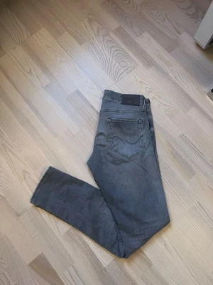 Grå slim jeans från Jack & Jones - Säljer ett par gråa slim fit jeans från Jack & Jones, modell Slim/Glenn. Jeansen har klassisk femficksdesign, normal midja och raka ben. Materialet är mjukt jeans med lite stretch för extra komfort. Snygg tvättad look och diskreta sömmar. W30 L32