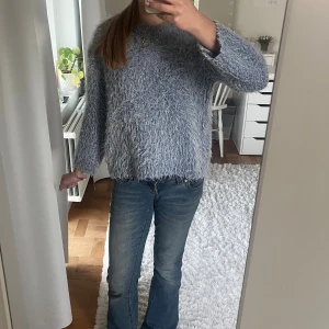 Fluffig mörkblå stickad tröja  - Supermysig ljusblå stickad tröja med fluffig textur och rund hals. Perfekt för kyliga dagar och ger en chill vibe till din outfit. Långärmad och loose passform som är både bekväm och snygg.