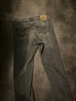 Replay grå jeans straight fit - Säljer ett par grå jeans från Replay med klassisk femficksdesign och snygga svarta sömmar på bakfickorna. Jeansen har en rak passform och är tillverkade i slitstarkt denim-material. Läderpatch med Replay-logga baktill i midjan. Storlek 30/30