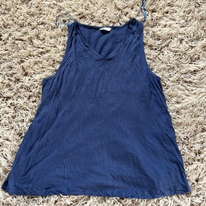 Blå linnetopp från Cubus - Säljer en blå linnetopp från Cubus i storlek L. Toppen har smala axelband och v-ringning framtill. Tillverkad i mjuk viskos som känns skön mot huden. Perfekt för varma dagar och enkel att matcha med jeans eller shorts.  Perfekt till sommaren.  Den är stretchig.