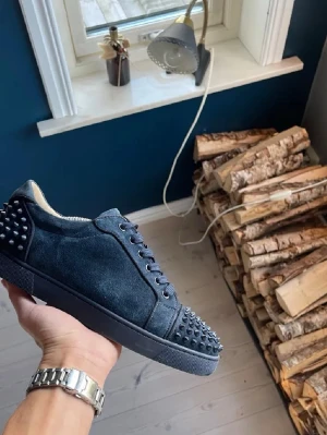 Christian Louboutin skor - Säljer ett par Christian Louboutin mörkblå sneakers i mocka med coola nitar på tån. Skorna har rund tå, platt sula och snörning. Insidan är i beige skinn och yttermaterialet är mjuk mocka. Perfekt för dig som vill sticka ut med din stil. Skicka till mig om det så att du vill ha fler bilder. Storlek är 42 men passar även till 43