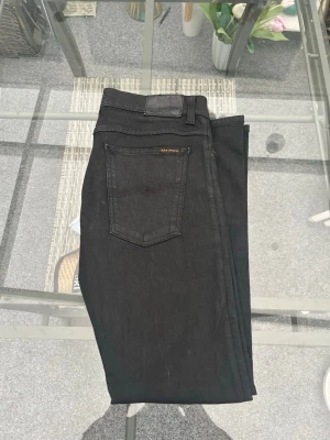 Nudie Jeans – Tight Terry – svarta slim jeans - Svarta Nudie Jeans Tight Terry i slim/tight passform med stretch. Riktigt clean look som funkar till allt – vardag, skola eller kväll. Klassisk 5-ficksmodell i bra kvalitet och bekvämt material.  • Storlek: W34 L32 • Modell: Tight Terry • Passform: slim / tight • Färg: svart • Material: 97% bomull, 3% elastan • Original Nudie Jeans • Använda men i fint skick  Perfekta om du vill ha stilrena jeans med bra passform och stretch 🔥  📦 Skickas snabbt 💬 Skriv om du undrar något 