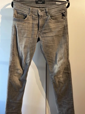 Replay Wallys grå jeans - Snygga grå jeans från Replay, modell Wallys. De har klassisk femficksdesign, svarta Replay-detaljer vid fickan och raka ben med diskret slitning. Materialet är mjukt jeans-tyg i bomull och polyester. Byxorna passar dig som är mellan 150-160 cm lång. De är använda men utan större skavanker. Nypris: 849kr