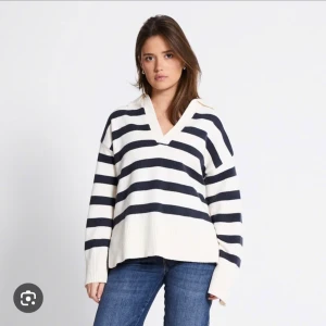 Randig stickad tröja med v-ringning - Säljer en stickad tröja med breda svarta och vita ränder. Tröjan har v-ringad hals, lång ärm och en loose passform. Perfekt för dig som gillar en avslappnad och trendig stil.