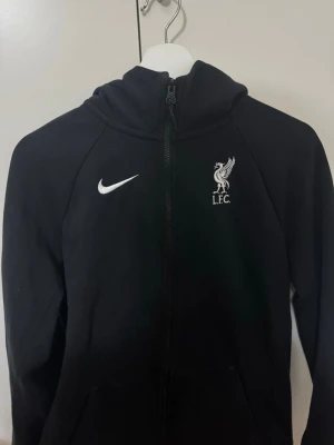Liverpool Zip tröja  - En oanvänd Liverpool zip tröja. Rikigt fin tröja. Storlek S men om du gillar den lite oversize så funkar det för Xs. Lite tight för en M storlek men kan funka.