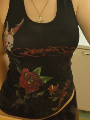 Ed Hardy linne - Ed hardy linne från ca 2009 (kommer inte ihåg exakt vilket år den är köpt) och använd sparsamt. Inga defekter. Små diamantstenar på rosorna på framsidan. Passar mig med xs/s men är stretchig så hade möjligtvis kunnat passa som en M. Pris går att diskutera.