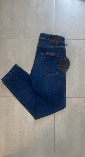 Helt nya Handpicked blå jeans, storlek 30 - Snygga blå jeans från handpicked som är helt nya och såklart även äkta. Jeansen är i topp skick och aldrig använd. Ett par lite lyxigare jeans för ett bra pris! Passar en grabb som är 167-175 ish. Passformen är slim/straight 