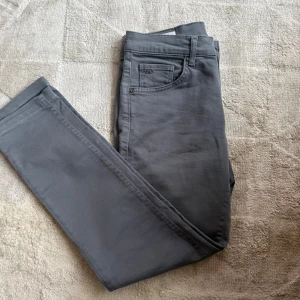 Grå slim Jeans från J.Lindeberg - Snygga grå Jeans från J.Lindeberg i slim passform. Byxorna har klassisk femficksdesign, bälteshällor och diskret JL-logga på myntfickan. Tillverkade i mjuk bomull med lite stretch för extra komfort. Perfekta till både sneakers och boots.