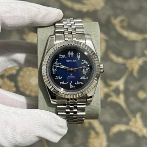 Seiko mode datejust - Unik Seiko automatisk dykarklocka med blå urtavla och roliga figurer som timmarkeringar. Boett och länk i silverfärgat stål, tydlig datumvisning och robust design. Urtavlan har en cool gradient från blått till svart. 