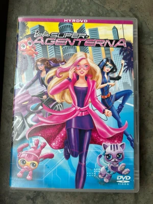 Barbie Super agenterna - Barbie och hennes bästa vänner Teresa och Renee är skickliga gymnaster som i det här actionfyllda äventyret får testa det spännande livet som hemliga superagenter!  Finns på språk: Svenska, Danska, Norska, Finska, Eng, Arabiska.   OBS!! skivorna är begagnade så det kan förekomma repor/hairlines på skivorna, men då jag kollar igenom alla filmer jag säljer garanterar jag att alla funkar felfritt om inget annat står! :)