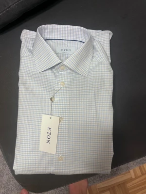 Rutig skjorta från Eton i bomull - Snygg rutig skjorta från Eton i ljusa toner av blått och vitt. Klassisk krage och knappar framtill. Tillverkad i mjuk bomull som känns skön mot huden. Perfekt för dig som gillar stilrena och fräscha plagg.