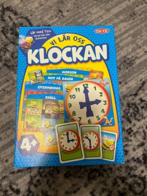 Vi lär oss klockan spel  - Bilderna visar ett spel för att lära sig klockan, men ingen väst finns med. Spelet innehåller färgglada kort och en klocka, men ingen klädesplagg som väst syns.