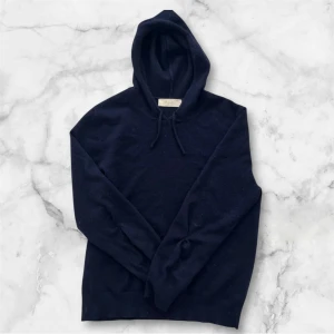 Mörkblå kashmir hoodie från Sayless - Mysig mörkblå hoodie från Soglios i lyxig kashmir. Tröjan har huva med snörning och långa ärmar. Perfekt för dig som gillar en stilren och enkel look med premiumkänsla. Passar dig som vill ha något både bekvämt och snyggt. Det finns lite hål som jag har sytt igen skriv till mig för att se dem