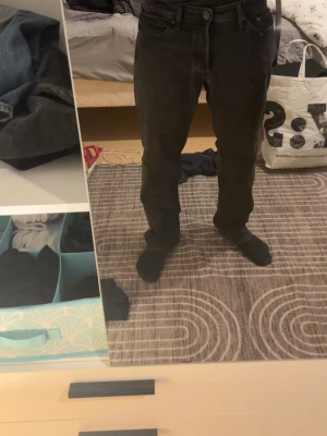 Svarta jeans från Jack Jones straight fit - Säljer ett par svarta jeans från Jack  Jones med klassisk femficksdesign och rak passform. Jeansen har midwaist och är tillverkade i bomull med en snygg mörk ton. Perfekta om du gillar en clean och enkel look. Säljer då den är för liten för mig