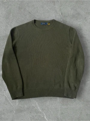 Olivgrön stickad tröja Polo Ralph Lauren | XL - Snygg olivgrön stickad tröja från Polo Ralph Lauren i storlek XL. Tröjan har rund hals, ribbade muddar och diskret broderad logga på bröstet. Perfekt för dig som gillar klassisk stil med en chill touch.
