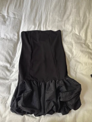 Svart kort klänning ASOS  - Säljer en svart axelbandslös kort klänning från ASOS DESIGN i storlek M. Passar perfekt nu till nyår 