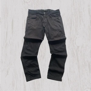 Replay Anbass svarta jeans, stl 31 - Svarta Replay Anbass jeans med klassisk femficksdesign och snygga detaljer. Jeansen har en rak passform och är tillverkade i mjukt bomullsmaterial med stretch för extra komfort. Perfekt för dig som gillar stilrena och tidlösa jeans.