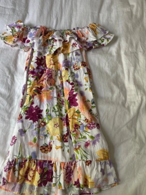 Blommig offshoulder klänning H&M - Supersöt kort blommig klänning från H&M i vitt med färgglada blommor. Perfekt nu till sommaren.