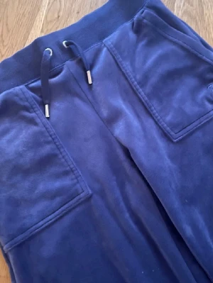 Mörkblå Juicy Couture byxa  - Fin byxa från Juicy Couture med fickor fram och bak. Fickor bak med knappar. Dragsko i midjan. Sparsamt använda så i fint skick. Storlek xs. 