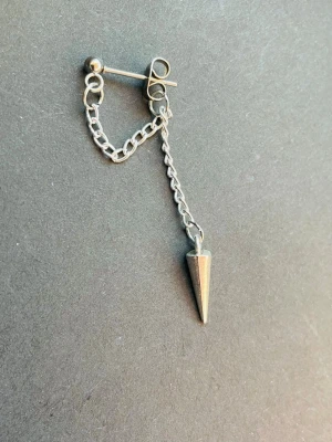 By prisförslag - 1 st Snyggt silverfärgad kedjeörhänge - Unikt örhänge i silverfärg med kedja och en spetsig kon i detalj. Perfekt accessoar för dig som gillar edgy och minimalistisk stil. Passar till både vardagslooks och mer alternativa outfits.