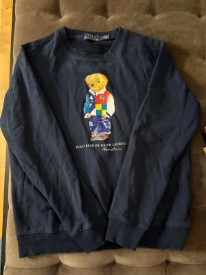 Ralph Lauren Polo Bear Tröja - Säljer en mörkblå långärmad tröja från Ralph Lauren i bomull, strl M. Använd ett fåtal gånger och i superskick. Hör av dig vid frågor eller lämna prisförslag.