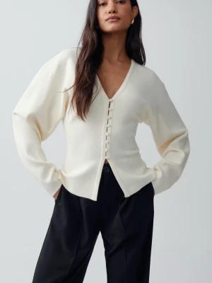 Vit kofta från Gina Tricot med knappar - Superfin vit kofta från Gina Tricot med v-ringning och klädda knappar framtill. Koftan har lång ärm och är gjord i mjukt material som känns skönt mot huden. Perfekt att styla med jeans eller kostymbyxor för en clean look.