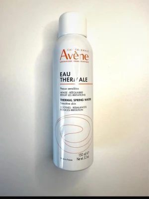 Avène Eau Thermale Face Mist 150 ml Ansiktmist Ny Oöppnad - Fräsch ansiktsspray från Avène i vit metallflaska med orange text och minimalistisk design. Innehåller 150 ml termalvatten som lugnar och återfuktar känslig hud. Perfekt för att ge huden en snabb boost under dagen. Ny, oanvänd och oöppnad.