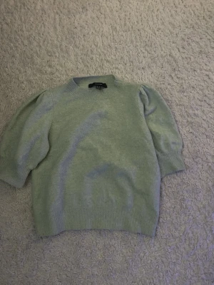 Ljusgrön stickad tröja Vero Moda - Supersöt ljusgrön stickad tröja från Vero Moda med puffärmar och ribbade muddar vid hals, ärmslut och nederkant. Tröjan har en mjuk och mysig känsla och är perfekt för lager på lager. Enkel men trendig design som passar till mycket.