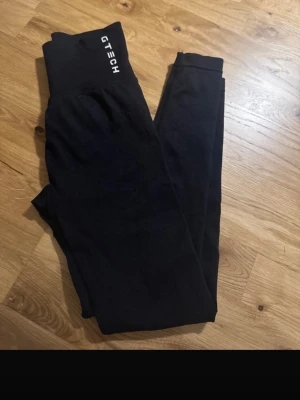 Svarta leggings från Gtech - Säljer ett par svarta leggings från Gtech med hög midja och stretchigt material. Perfekta för träning eller chill. Diskret logga framtill i midjan och tight passform som framhäver figuren. Har ett hål på låren tyvärr och därav går jag ner i pris 